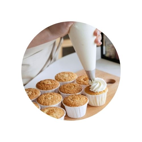 Mains glaçant des gâteaux à l'aide d'une poche à douille.